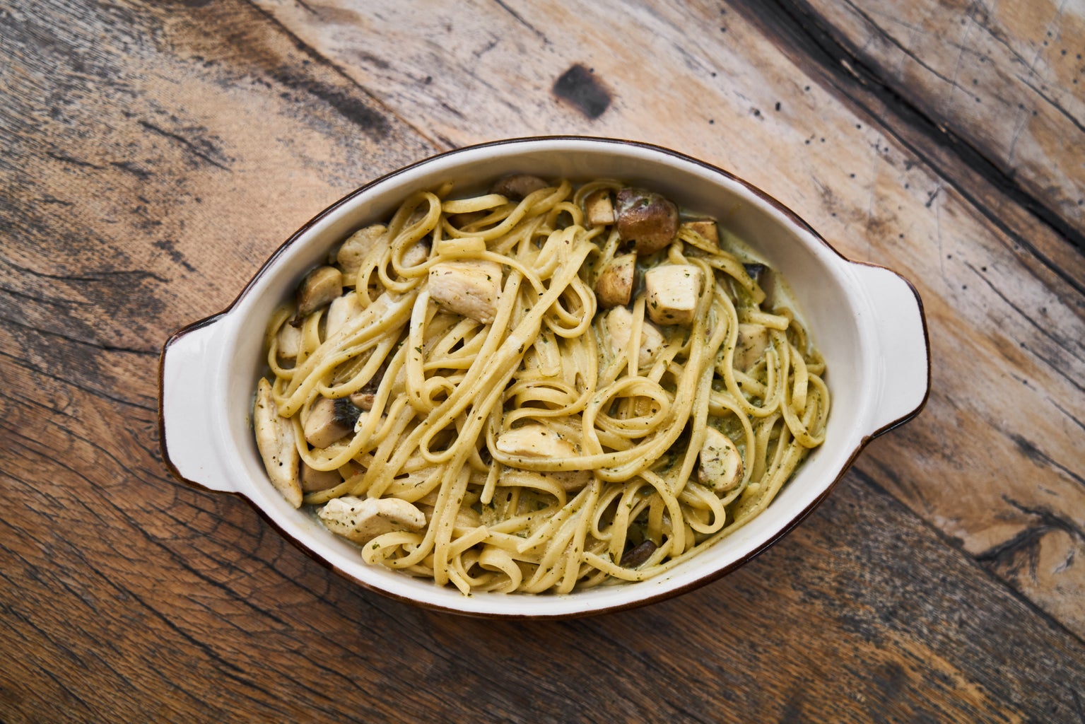 white bowl with pasta in it on a wood table