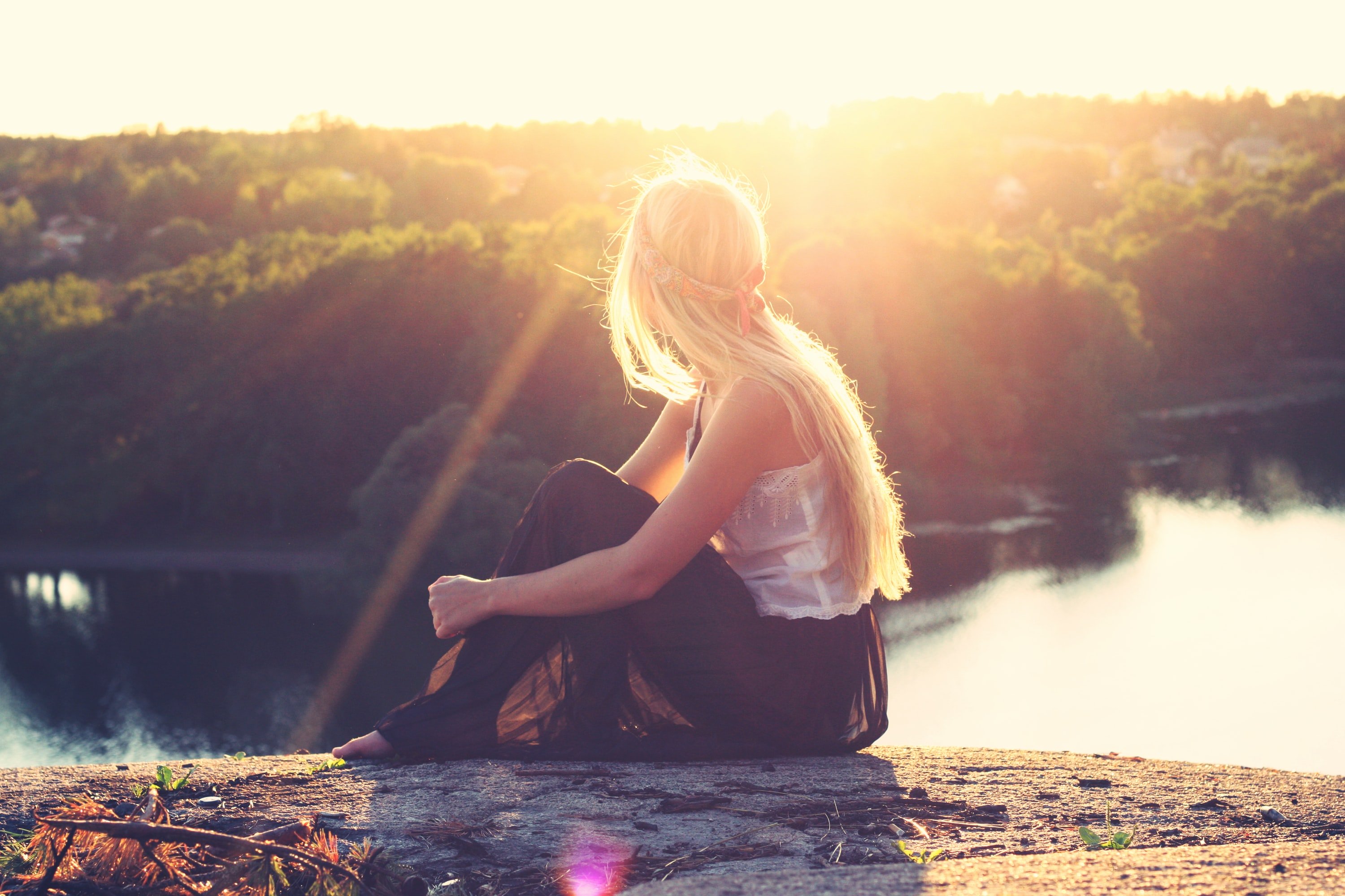 woman sitting on a rock overlooking a lake
