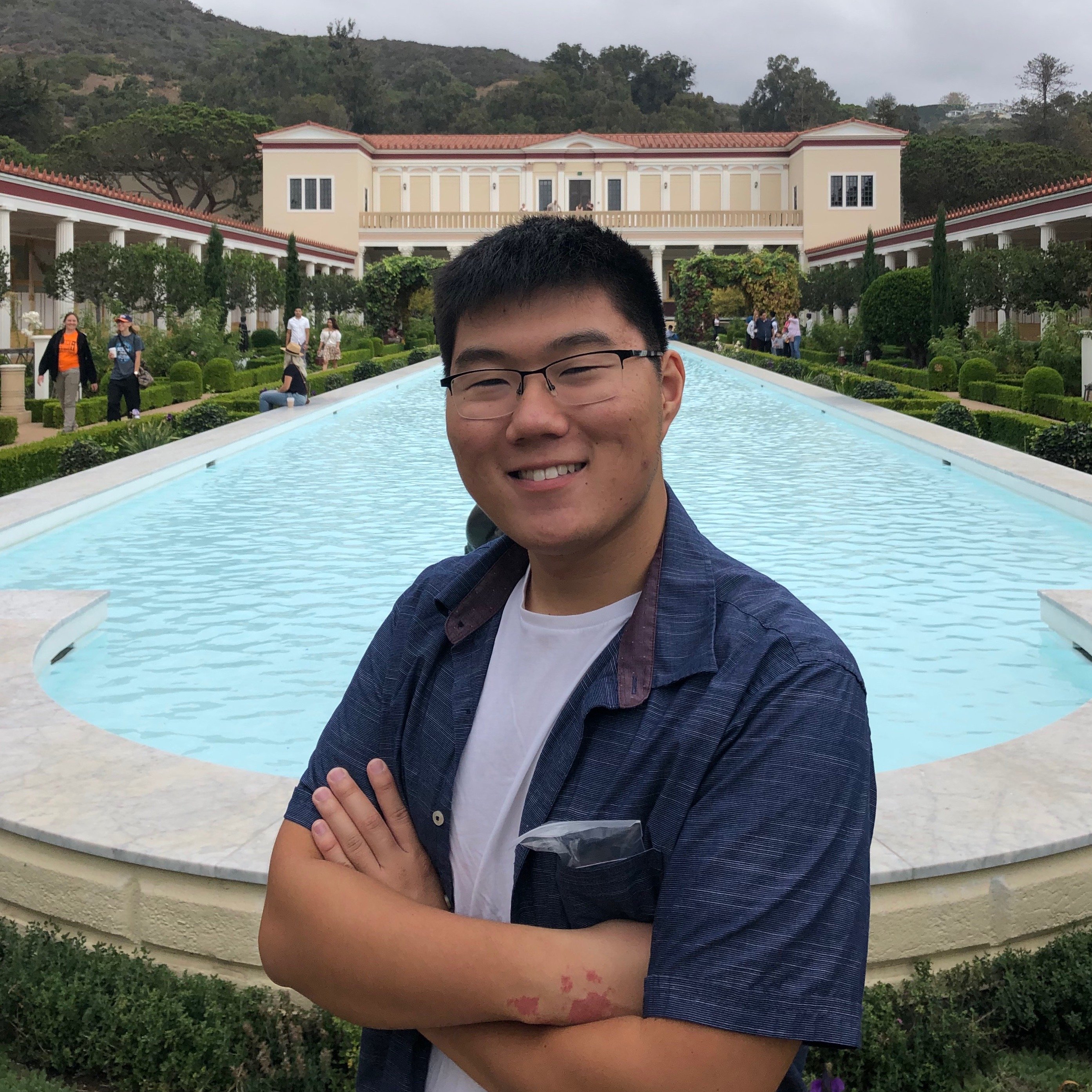 boy standing in front of a pool, wearing a blue shirt