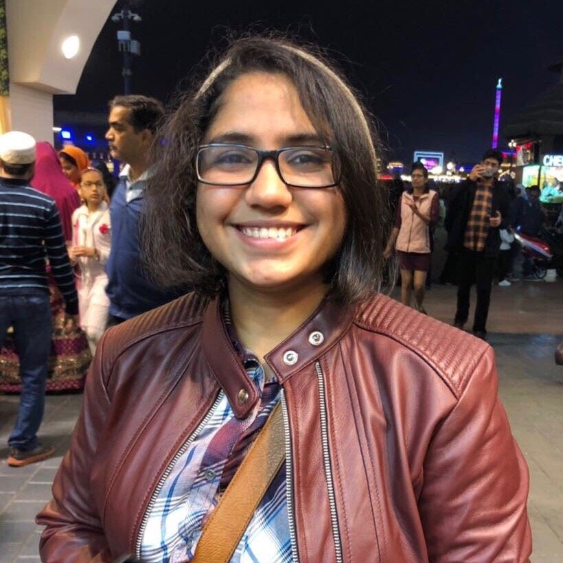 girl with short black hair and glasses, wearing a maroon leather jacket
