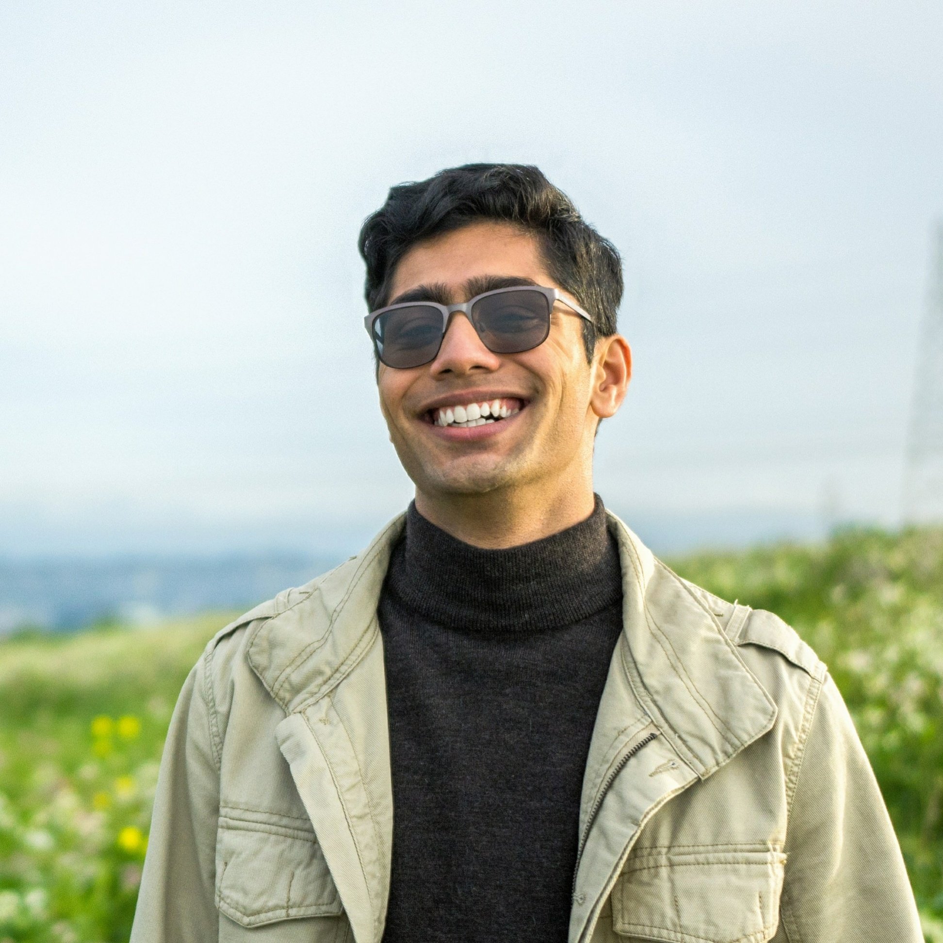 boy with glasses wearing black turtleneck and beige jacket