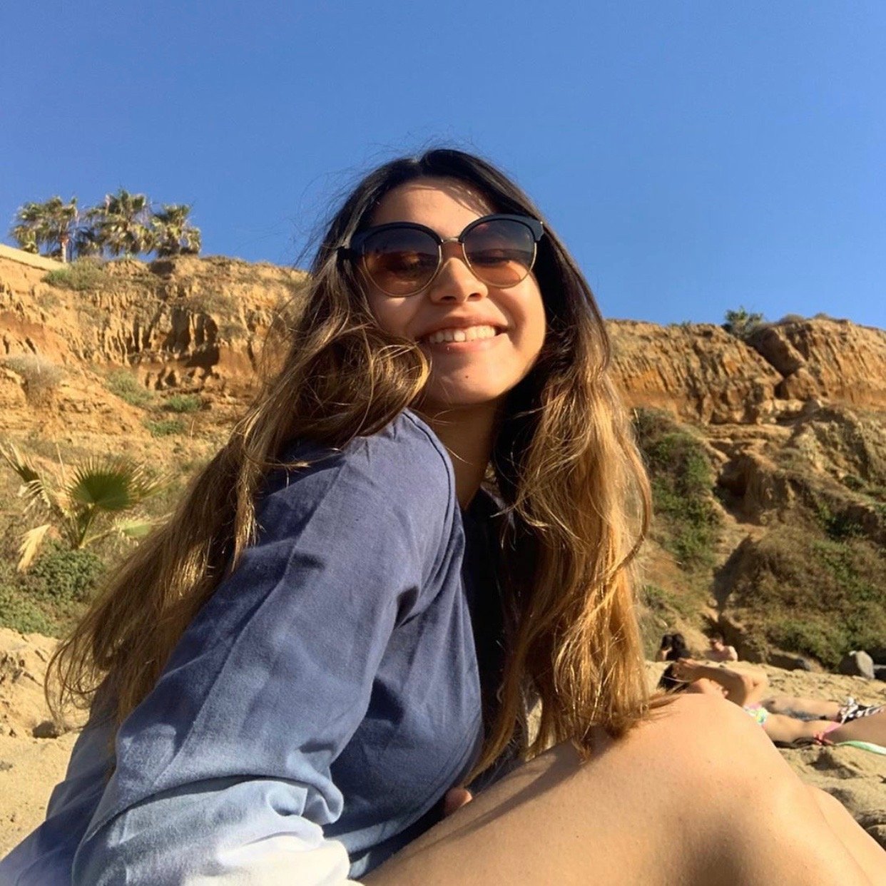 girl at the beach with sunglasses and blue shirt