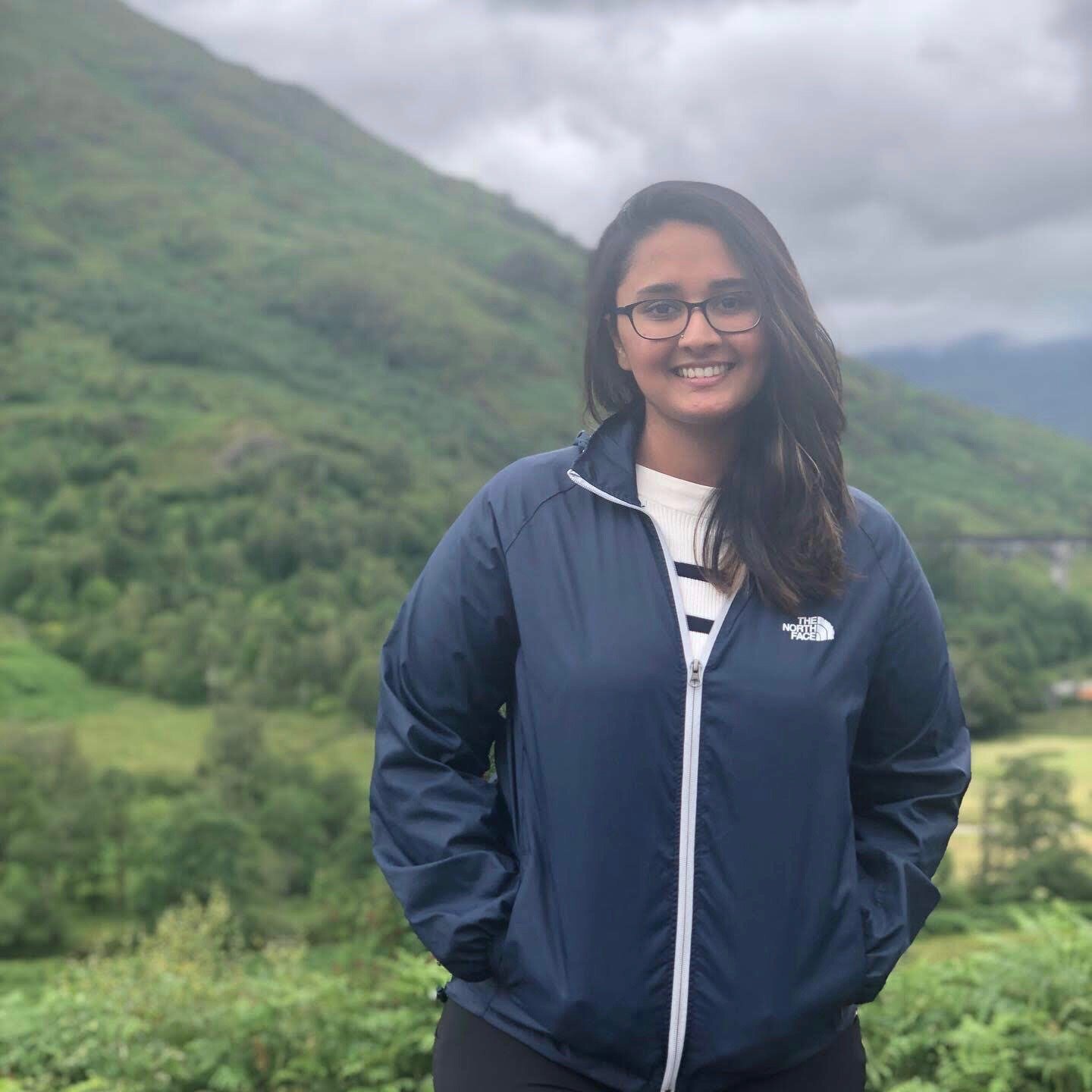 girl standing in front of mountains with glasses and a NorthFace windbreaker
