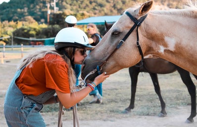 girl in overalls kissing horse