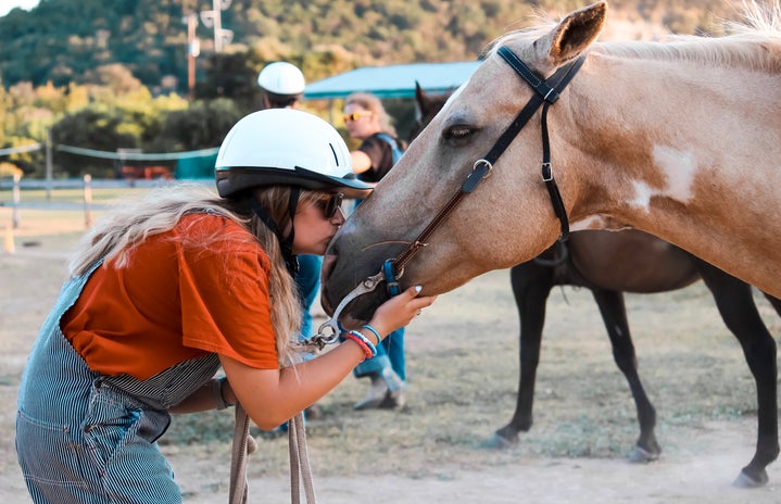 girl in overalls kissing horse