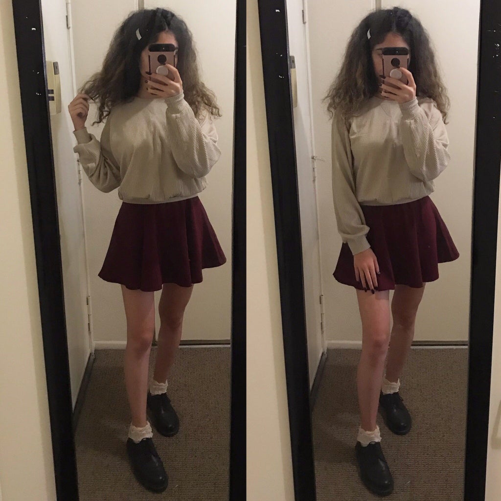 mirror selfie of a girl wearing a beige sweater and red pinafore skirt