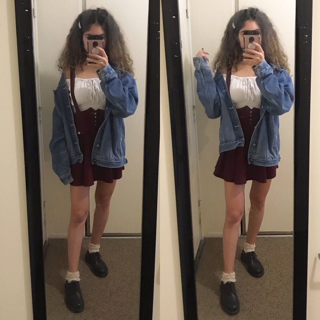 mirror selfie of a girl wearing a crop top, denim jacket, and red pinafore skirt