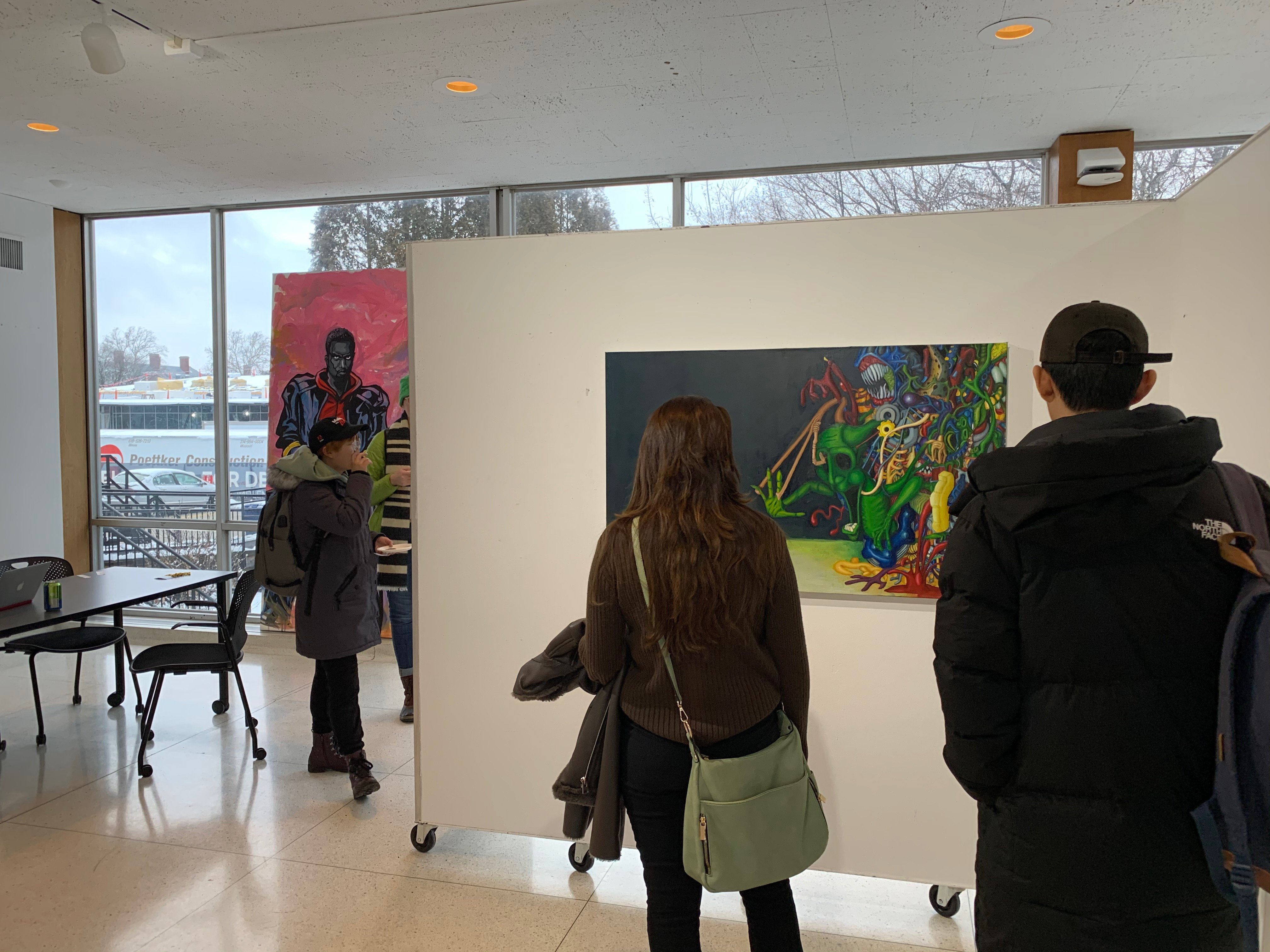 People viewing and walking around an exhibition/gallery.