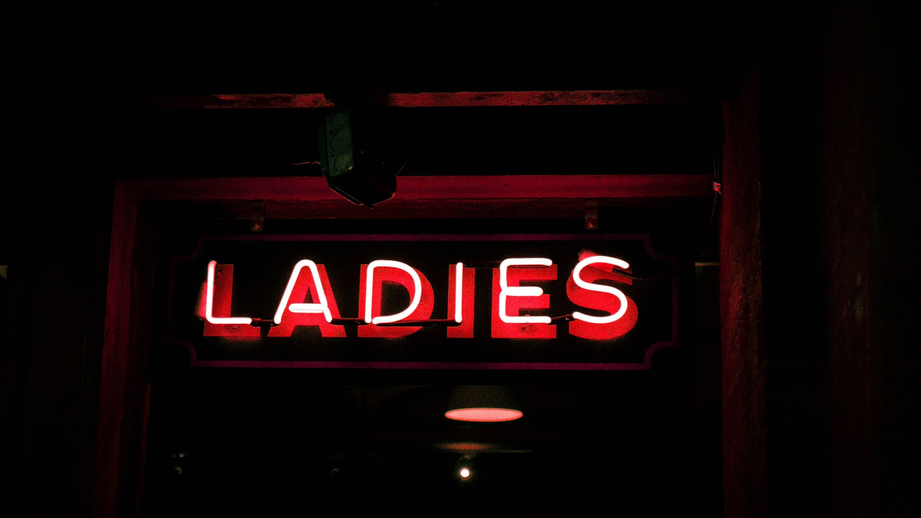 Red neon light singnage that says 'ladies'