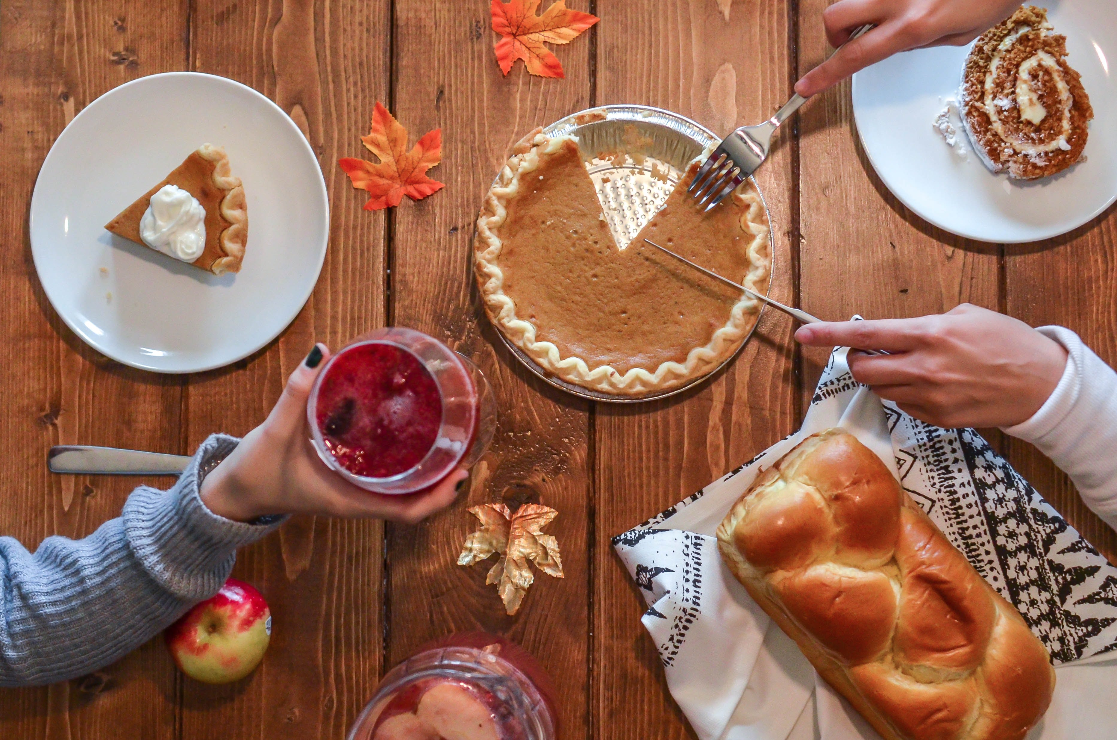 wooden dinner table with pie, bread, and cake