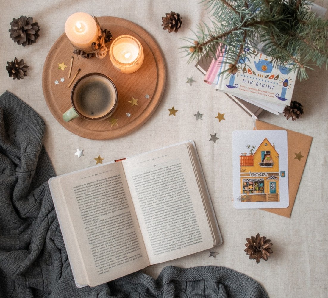 A candle, books, and a mug upon a white surface