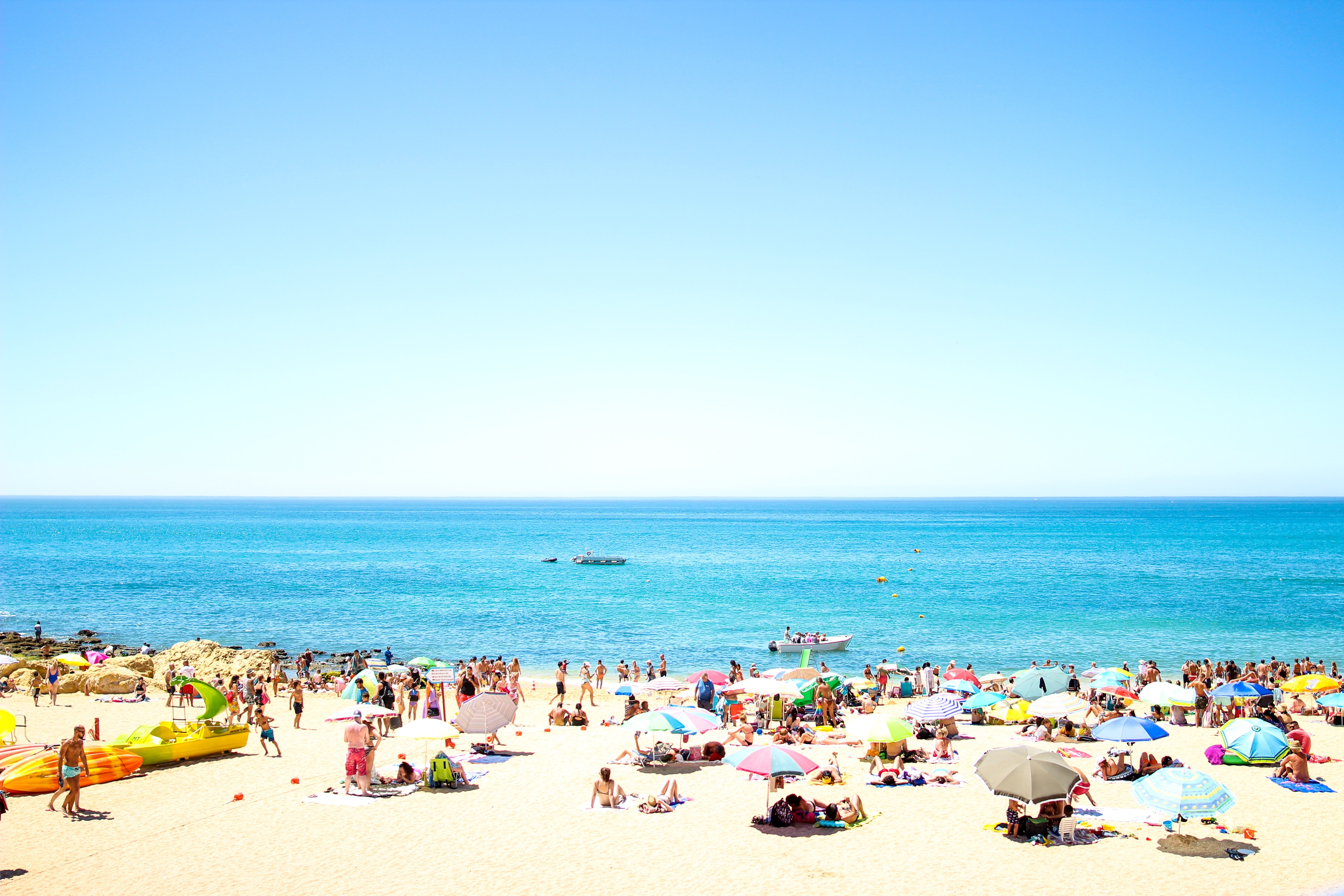 crowd on beach under blue sky Oliveira
