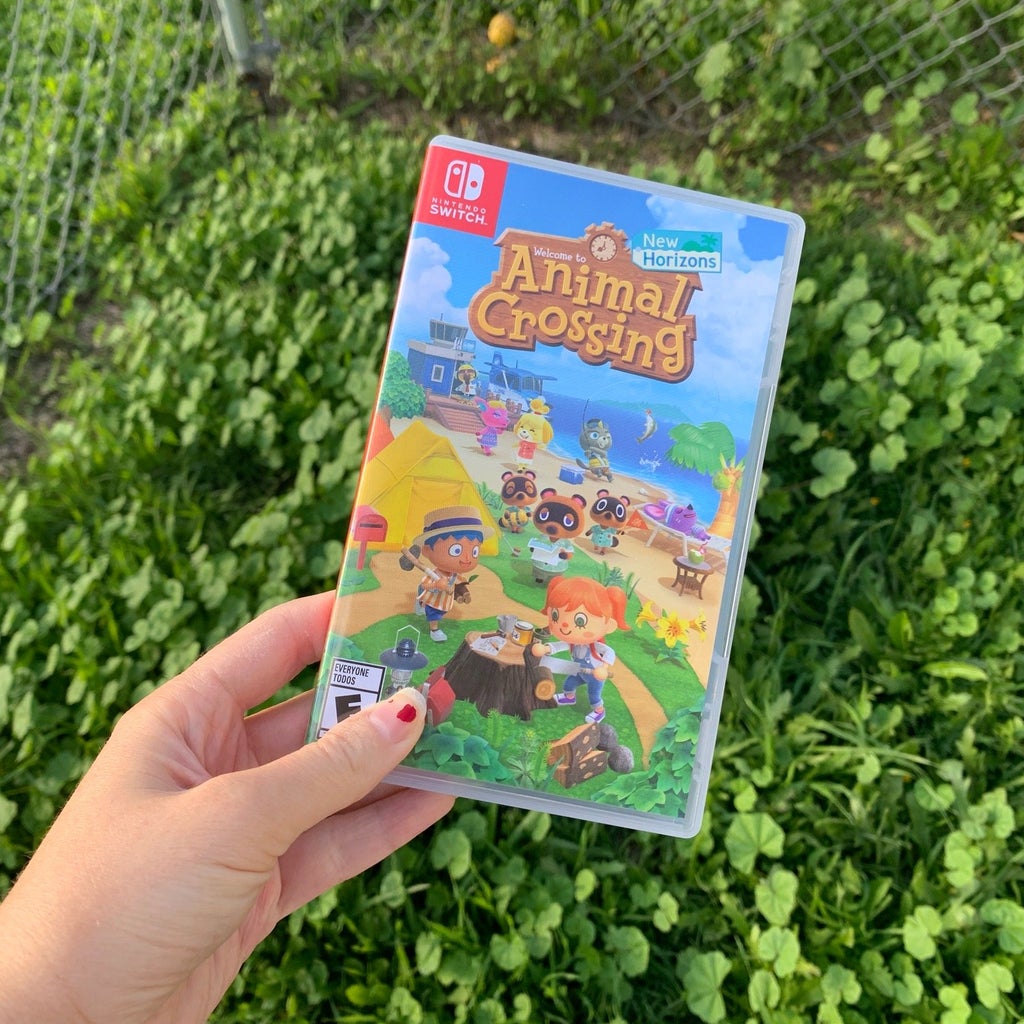 animal crossing game being held up in front of some grass