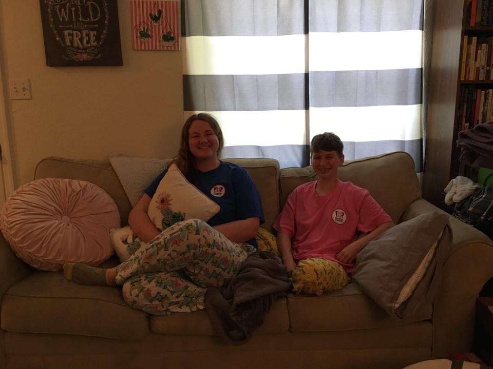 Devon and Lindsey sit on their couch with matching pajamas