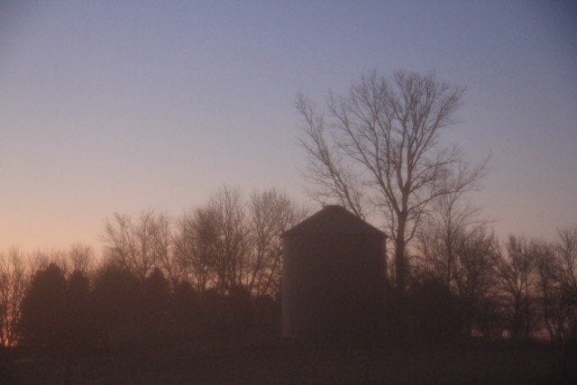 Silhouette of a farm at sunset.