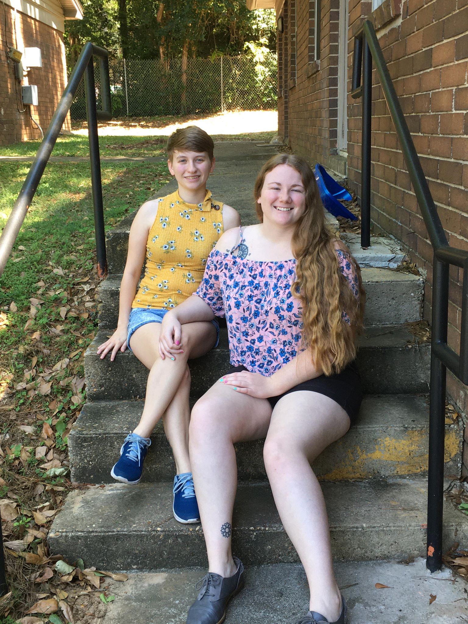 Devon and Lindsey pose on stairs in floral shirts