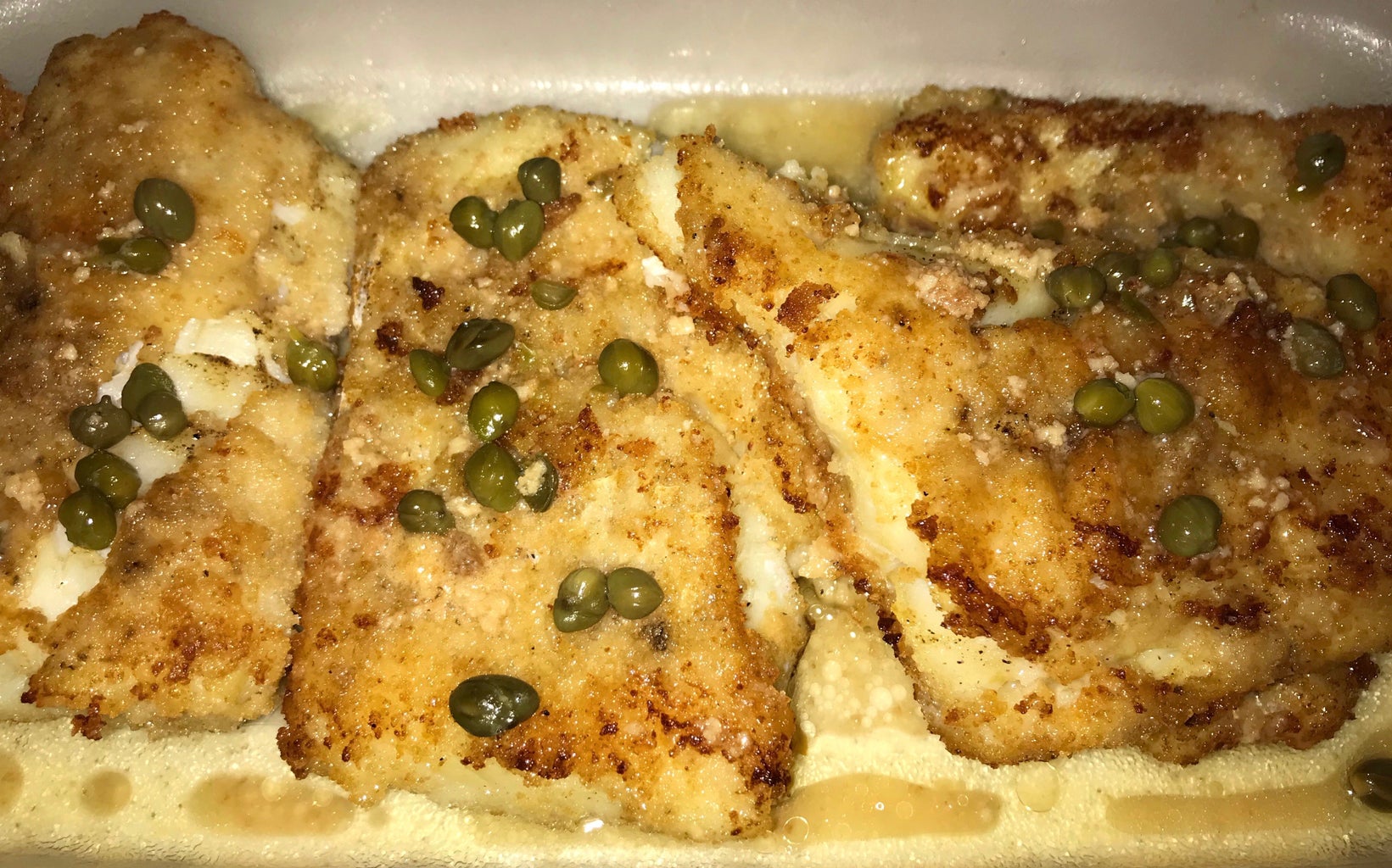 a tray of fried fish with capers