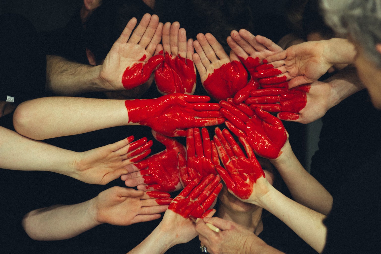 a bunch of hands with red paint on them forming a heart