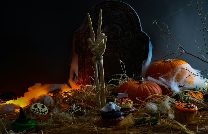 peace sign skeleton hand coming out of grave with pumpkins