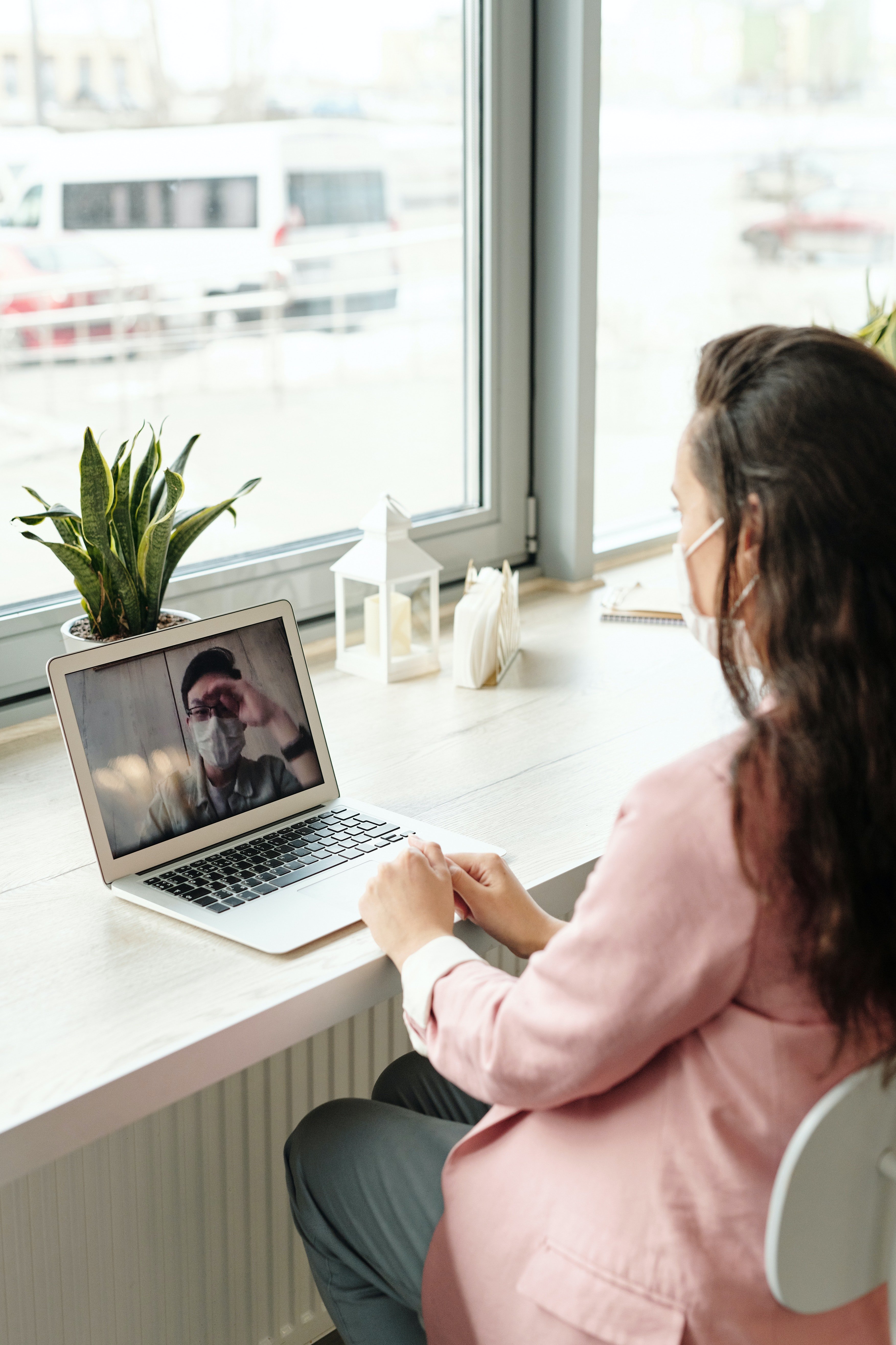 woman with a mask using her laptop to video chat someone also with a mask