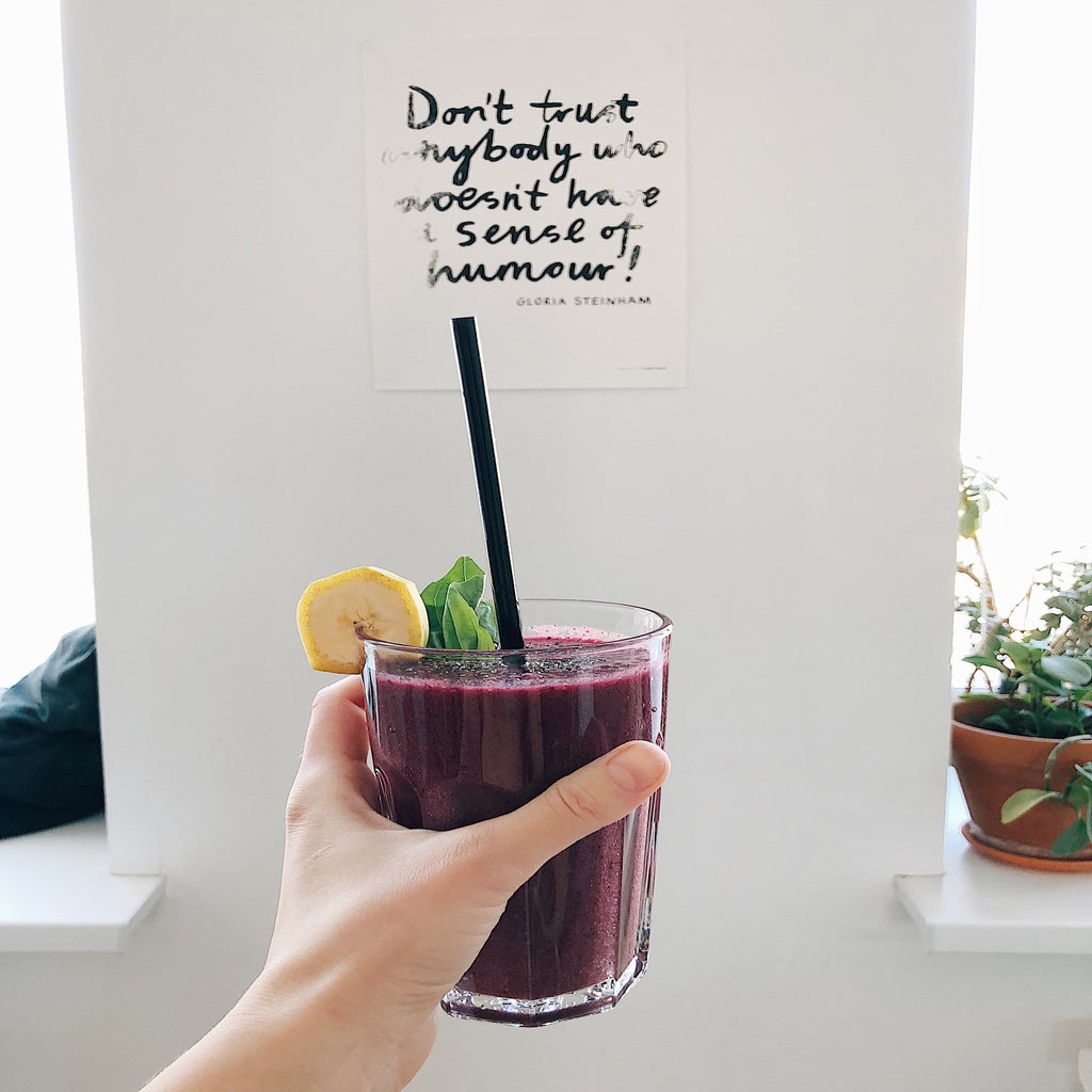 person holding drink with wall that says \