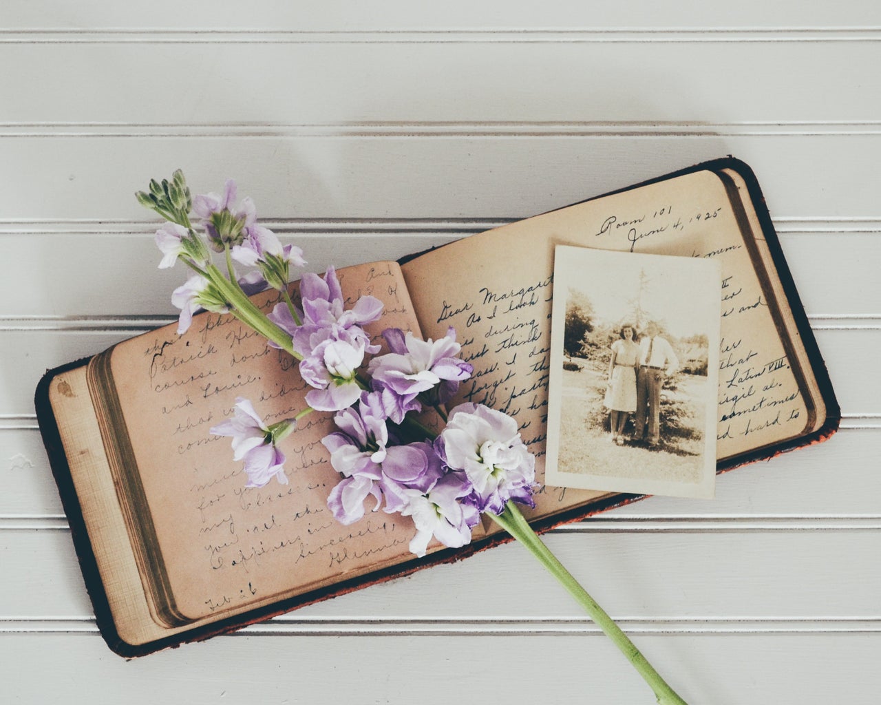 purple flowers on brown open book with black and white photograph