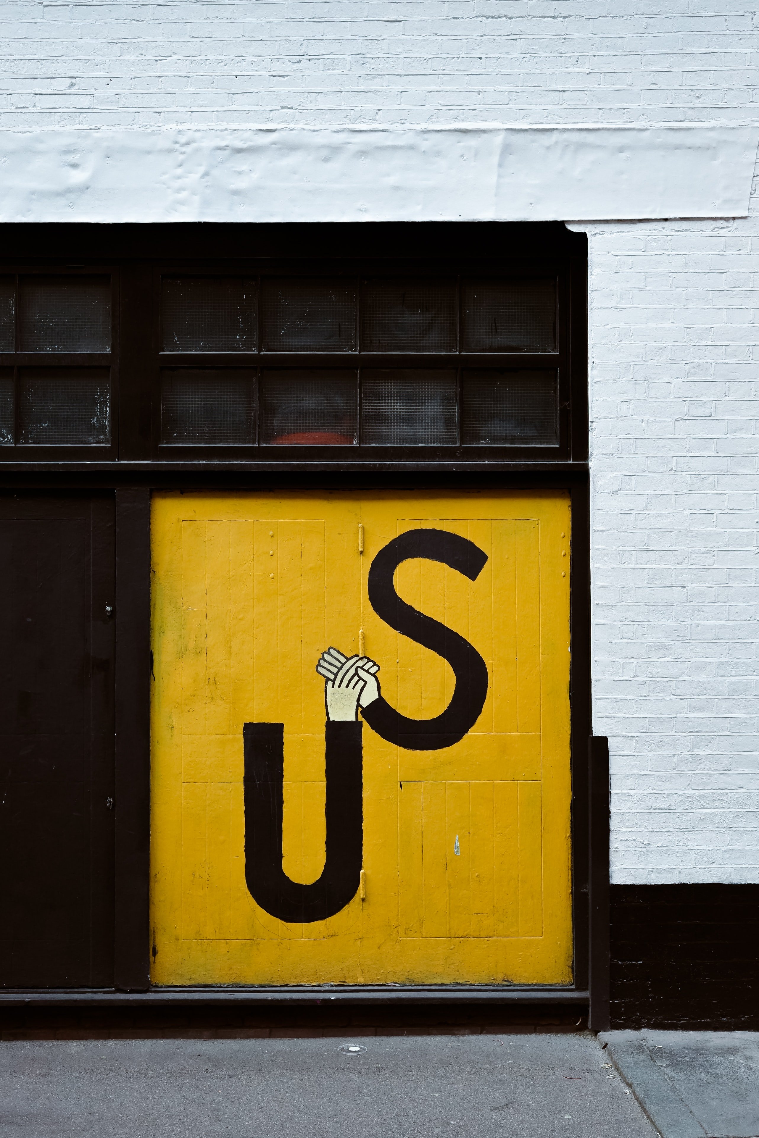 painted hands holding with \"US\" on a black steel gate