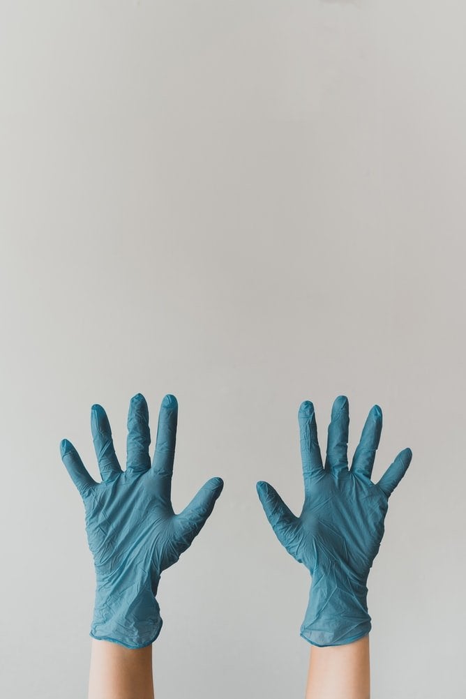 Two hands covered by blue gloves rising up into the air