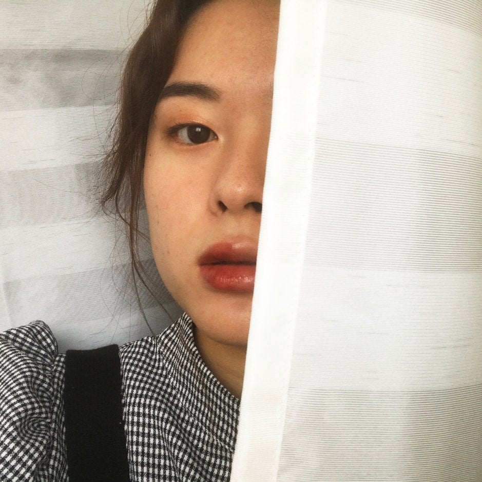 Image of chapter member showing half of face with makeup, while hiding the other half with a curtain