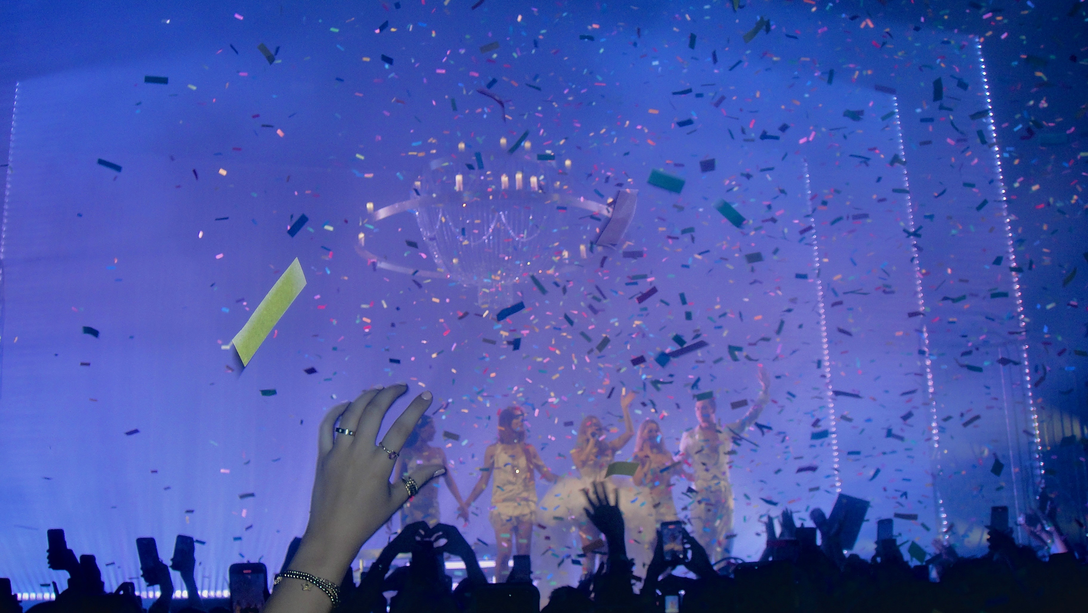 fans cheering at concert while confetti falls