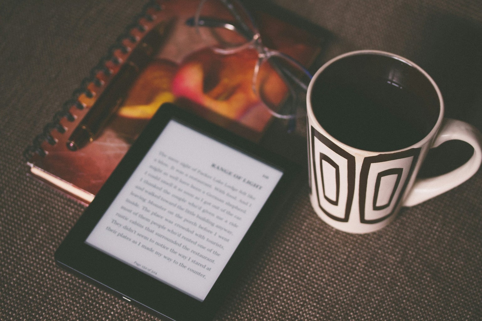 black ebook reader next to coffee cup