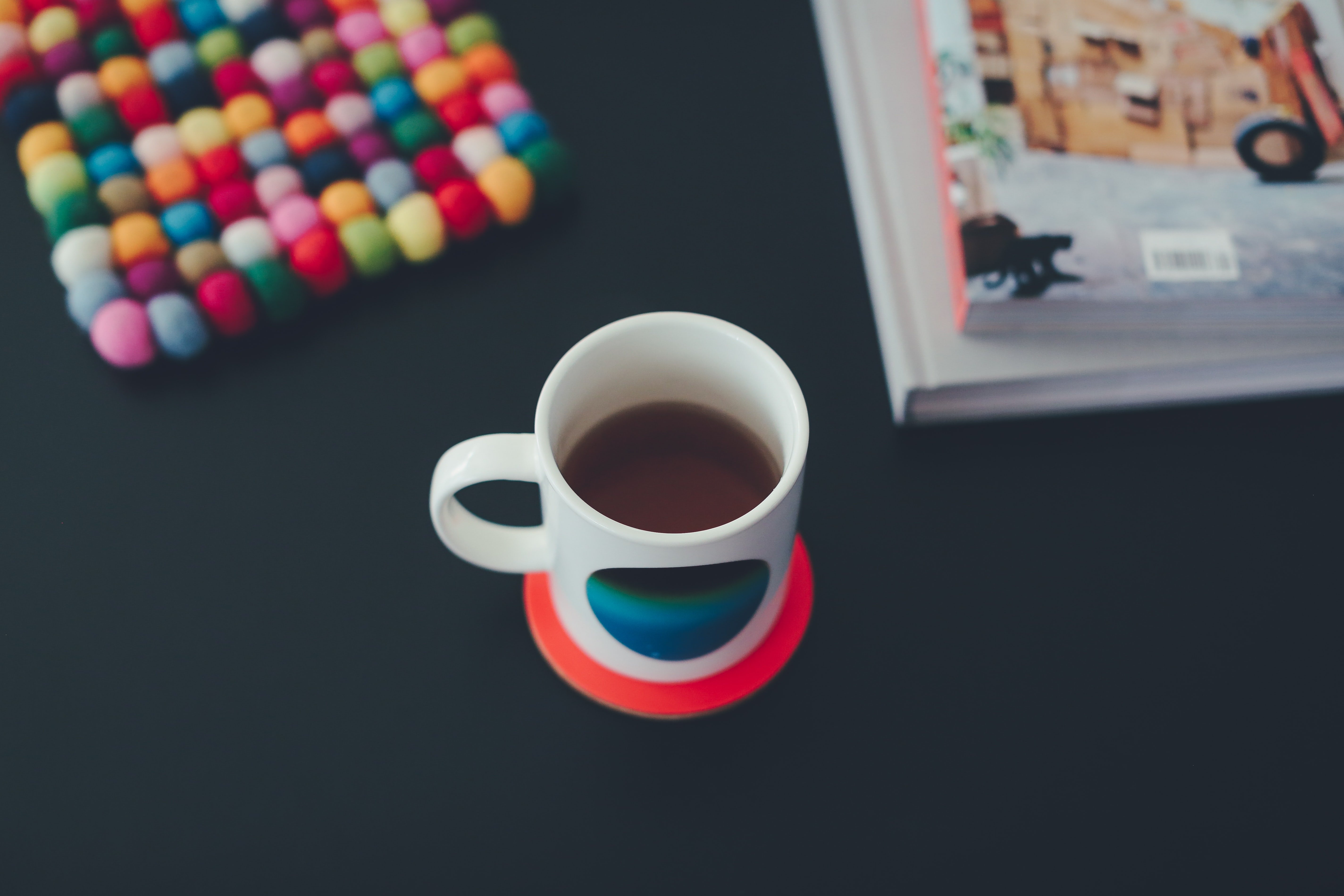 Coffee mug on table with books and colorful pot holder