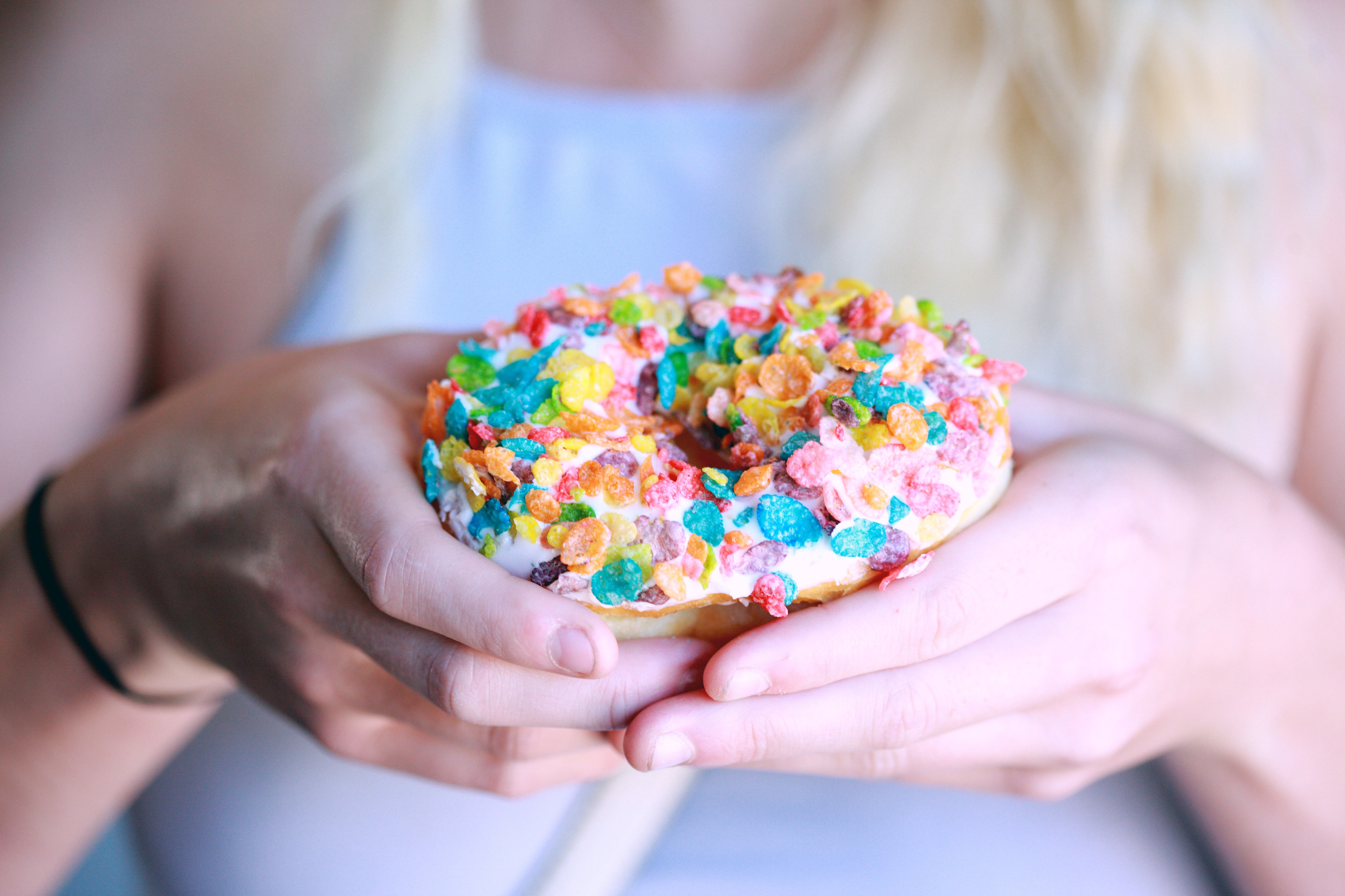 person holding doughnut with toppings 1200655