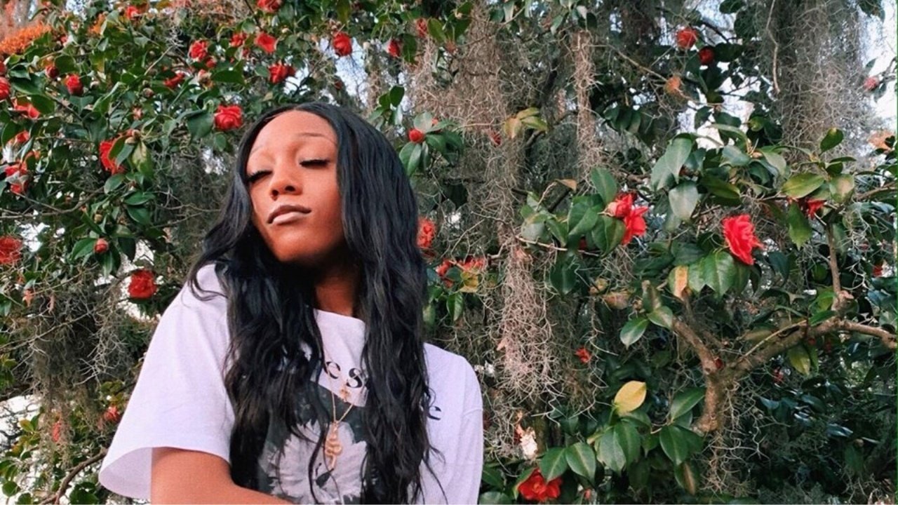 Girl in a white shirt in front of an ivy and roses-covered wall