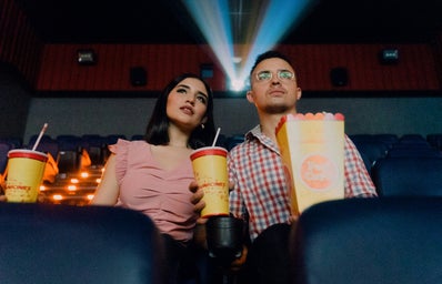 two people looking at screen in theatre with popcorn