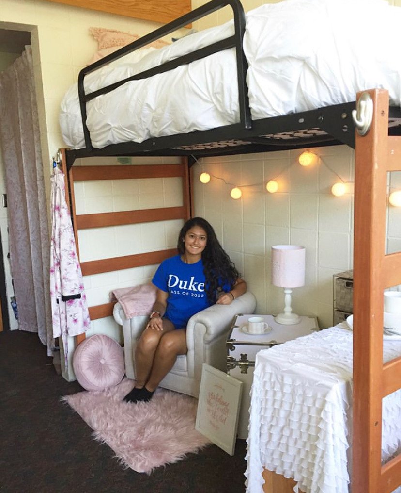 An image of the author sitting on the bed in her dorm.