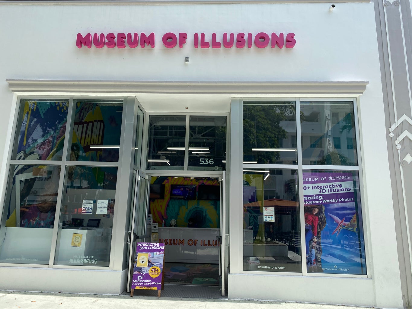 Entrance to Museum of Illusions, white building with pink letter title.