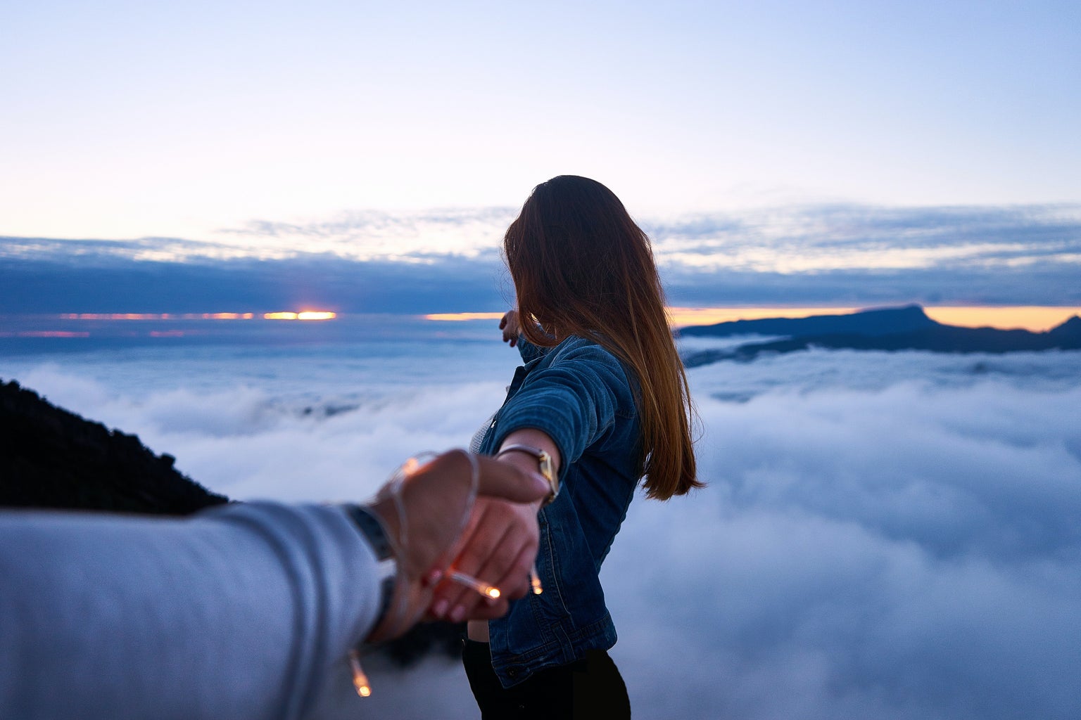 person holding woman\'s hand on top of hill