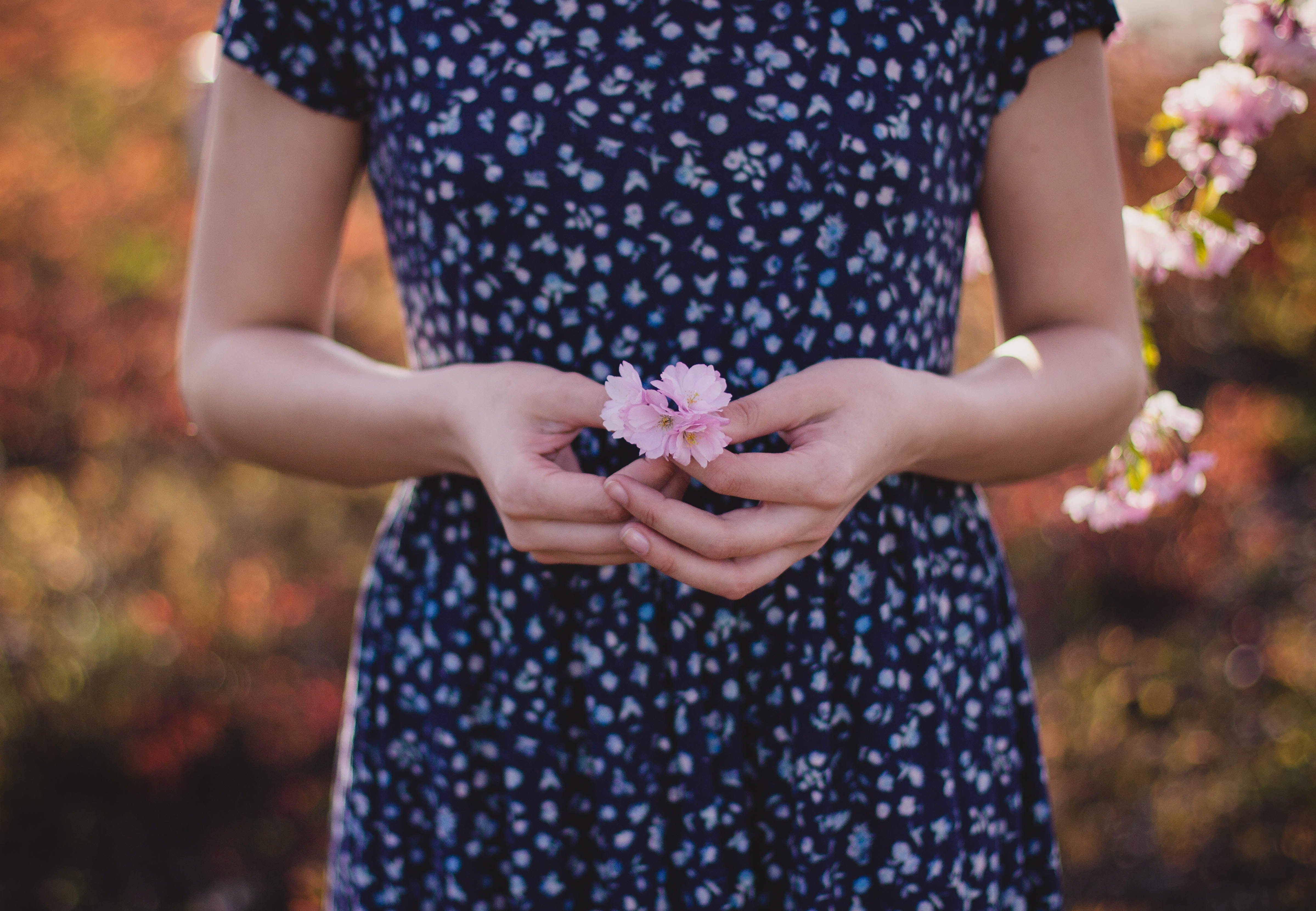 woman in blue dress holding a pink flower