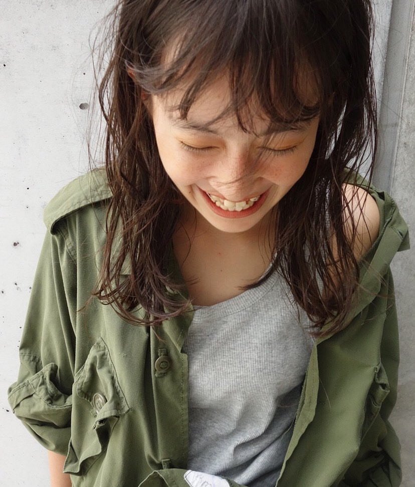 girl smiling with eyes closed, wearing gray tank top with open green button down