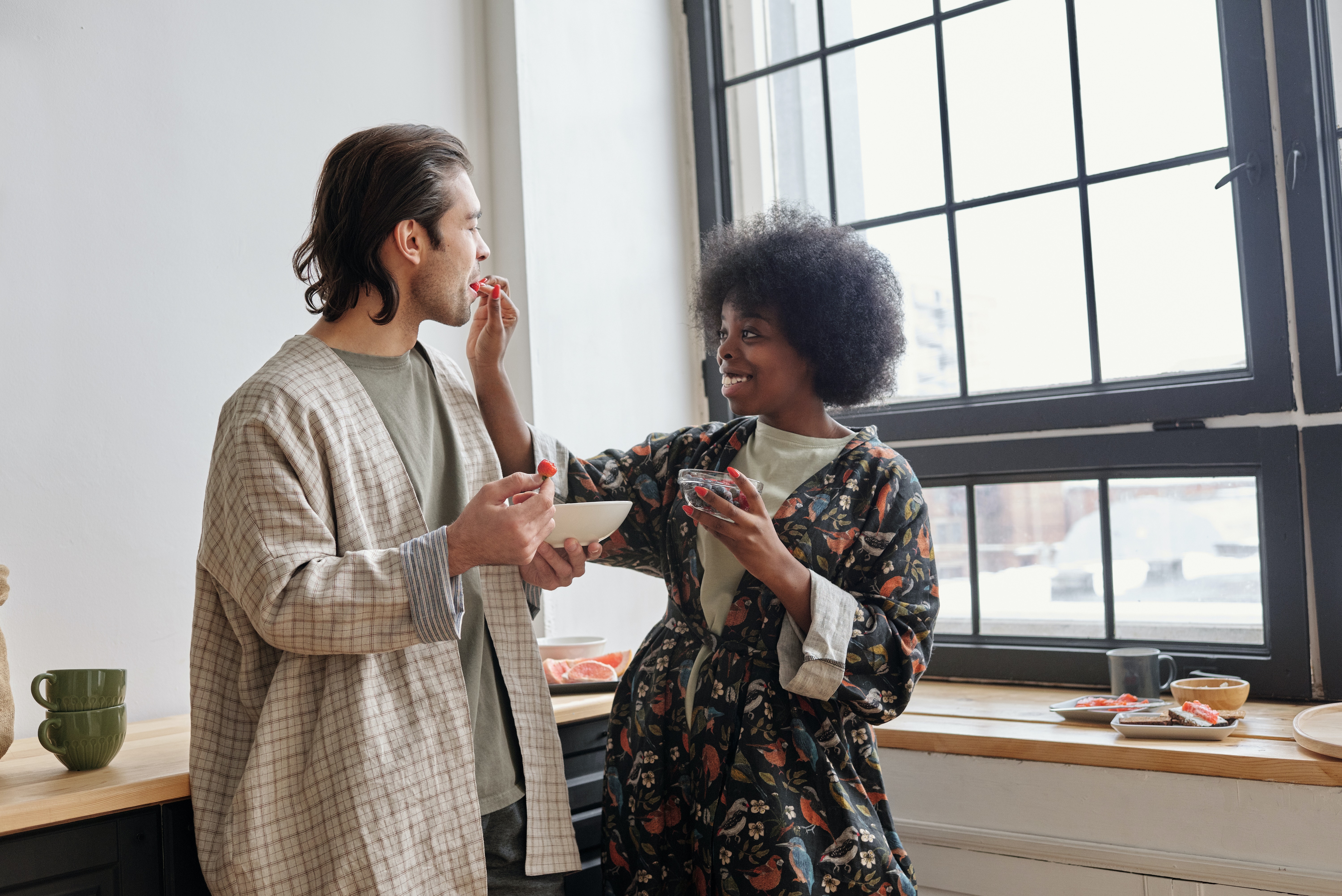 woman feeding strawberries to a man and smiling