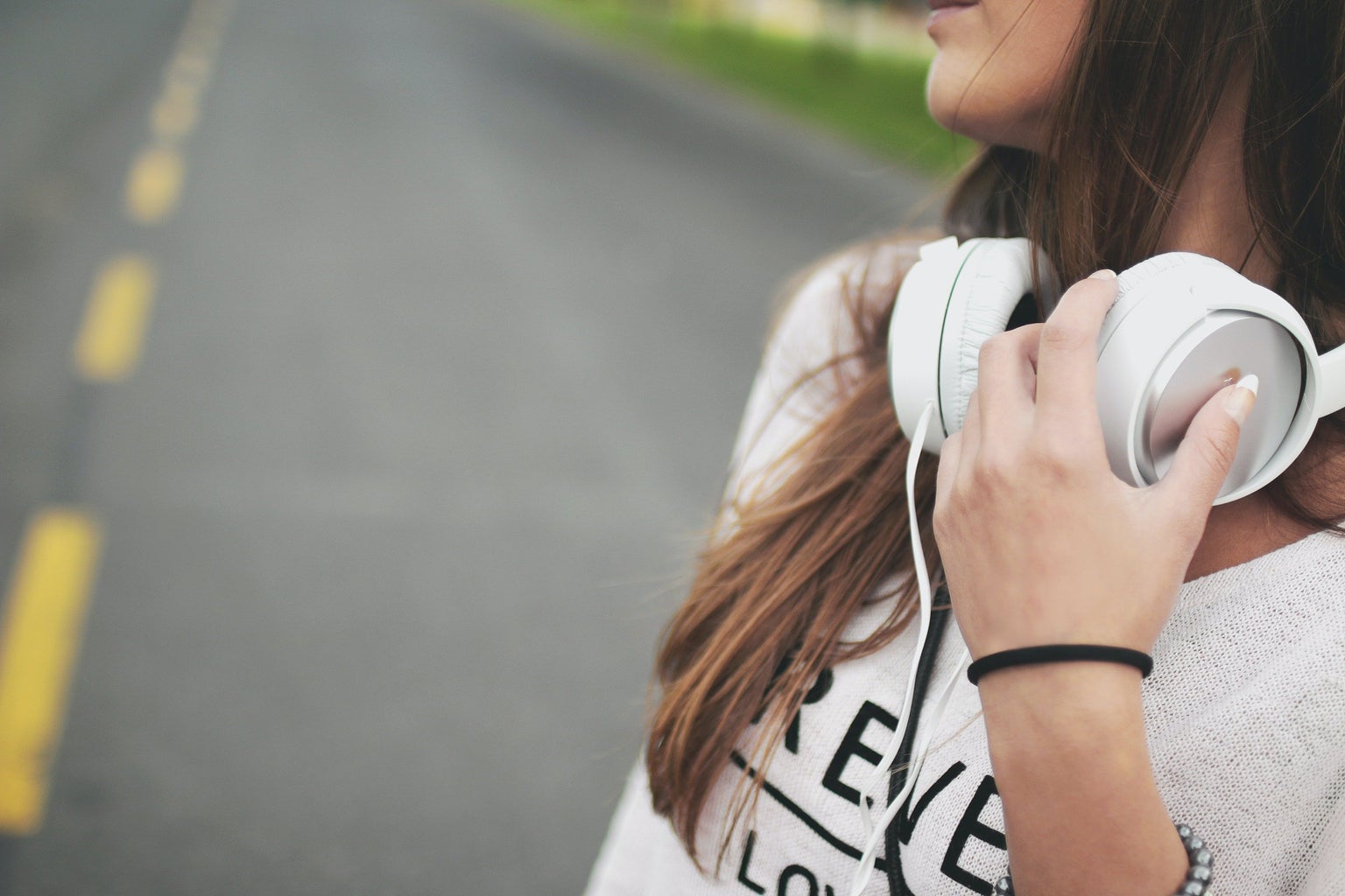 close-up of woman holding white headphones around her neck