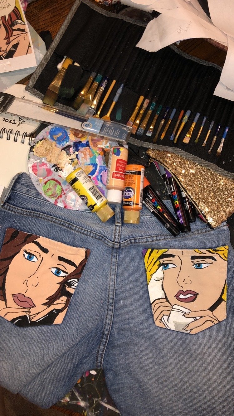 Painted jeans with paint bottles and brushes around them