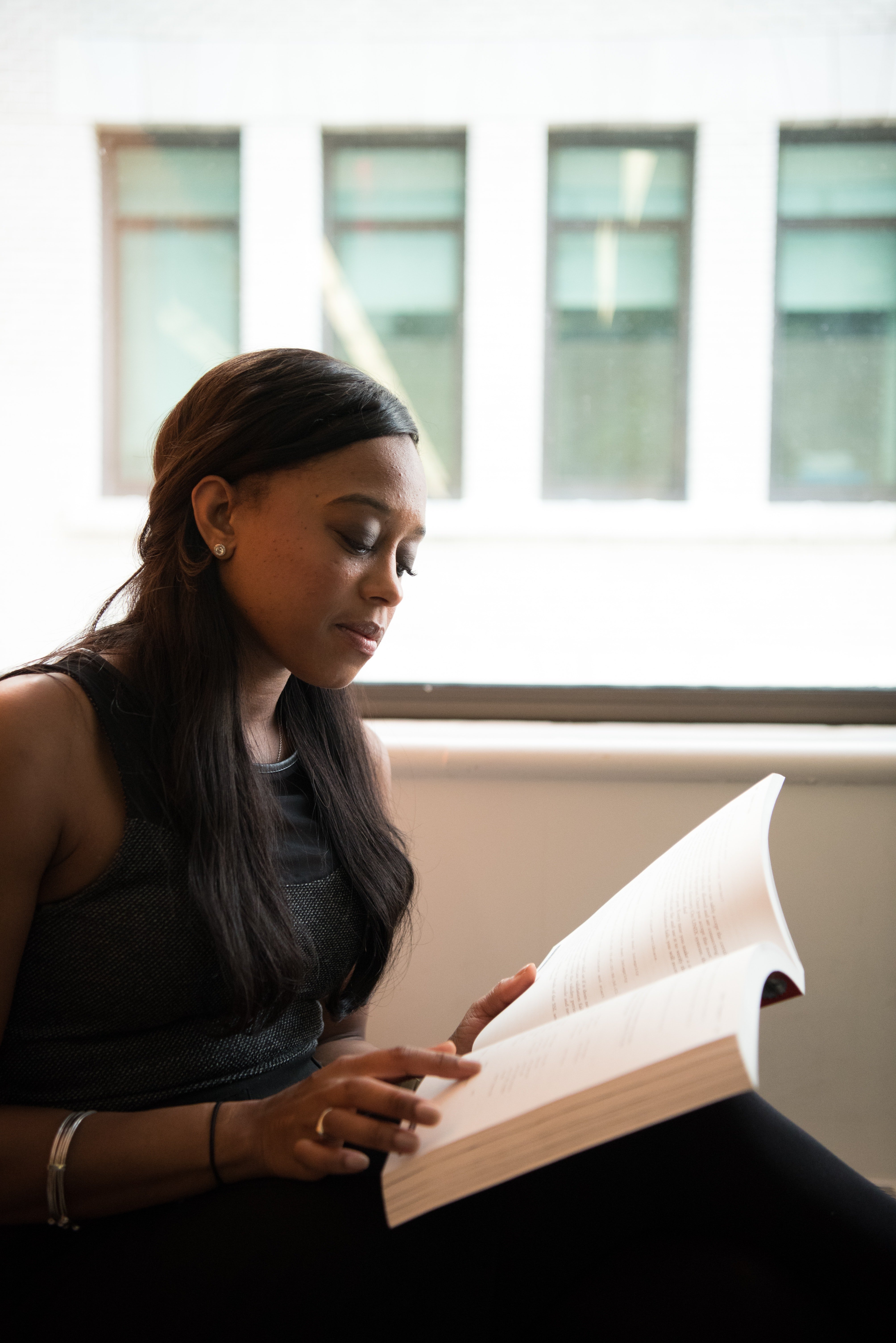 woman reading book by window by Christina Morillo