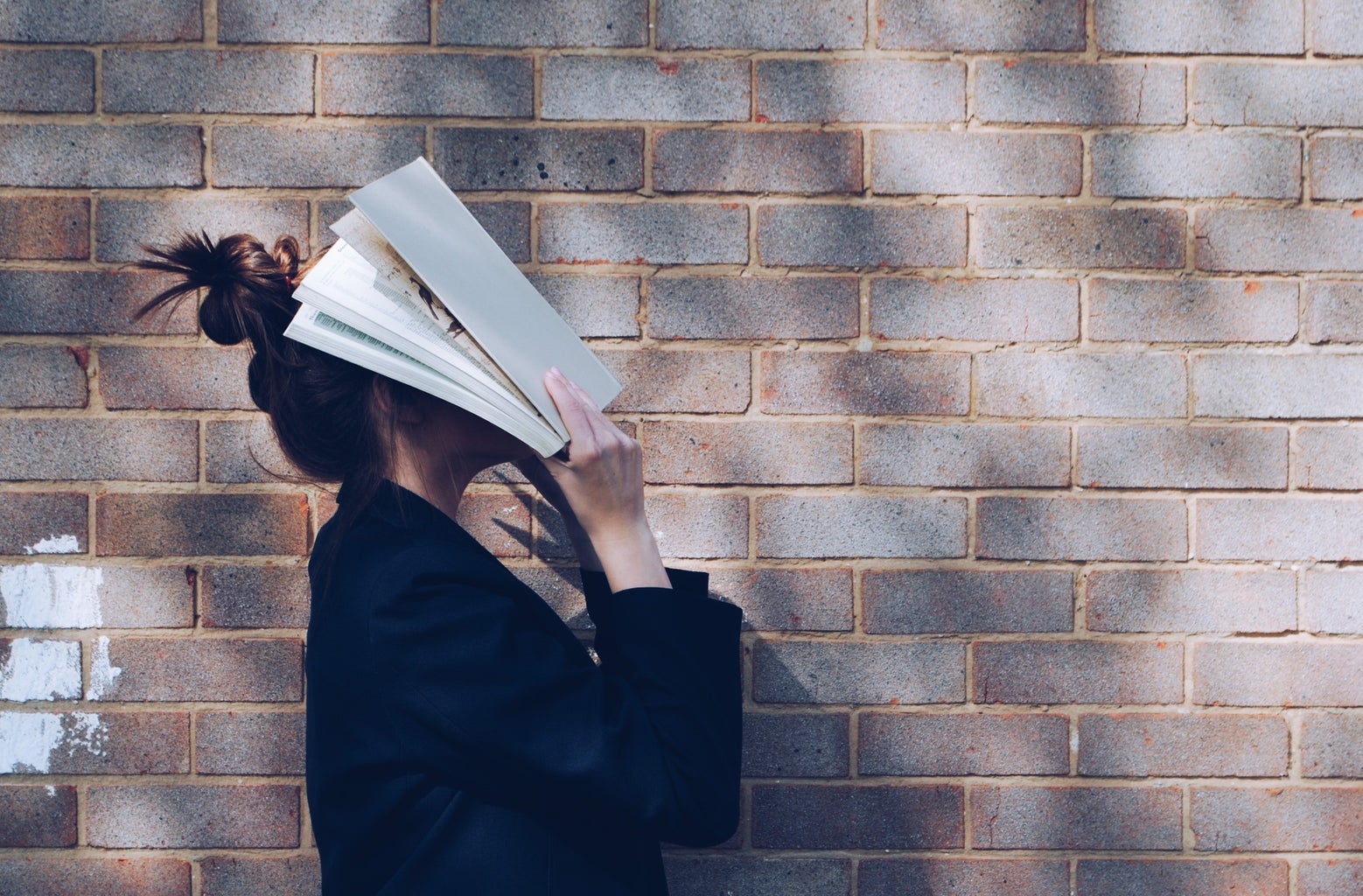 Girl covering face with book