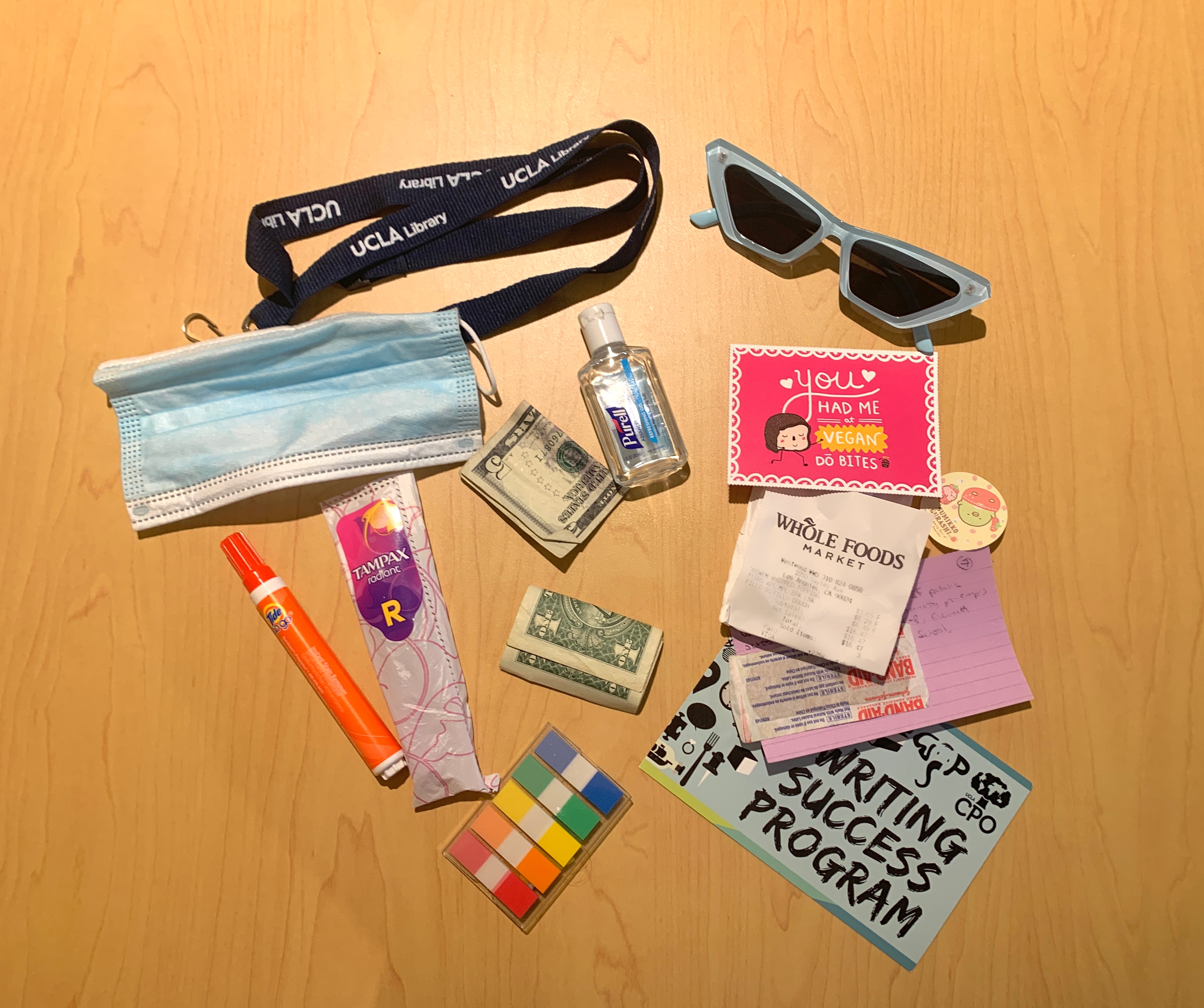 Miscellaneous purse items like a receipt, a tampon and hand sanitizer.