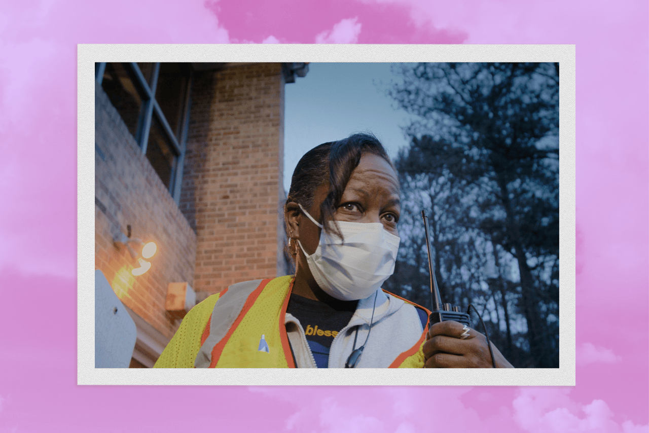 Tracii, head of security at a women’s health clinic in Atlanta, wears a mask and safety vest while holding a walkie-talkie in HBO’s documentary “The Devil Is Busy.”