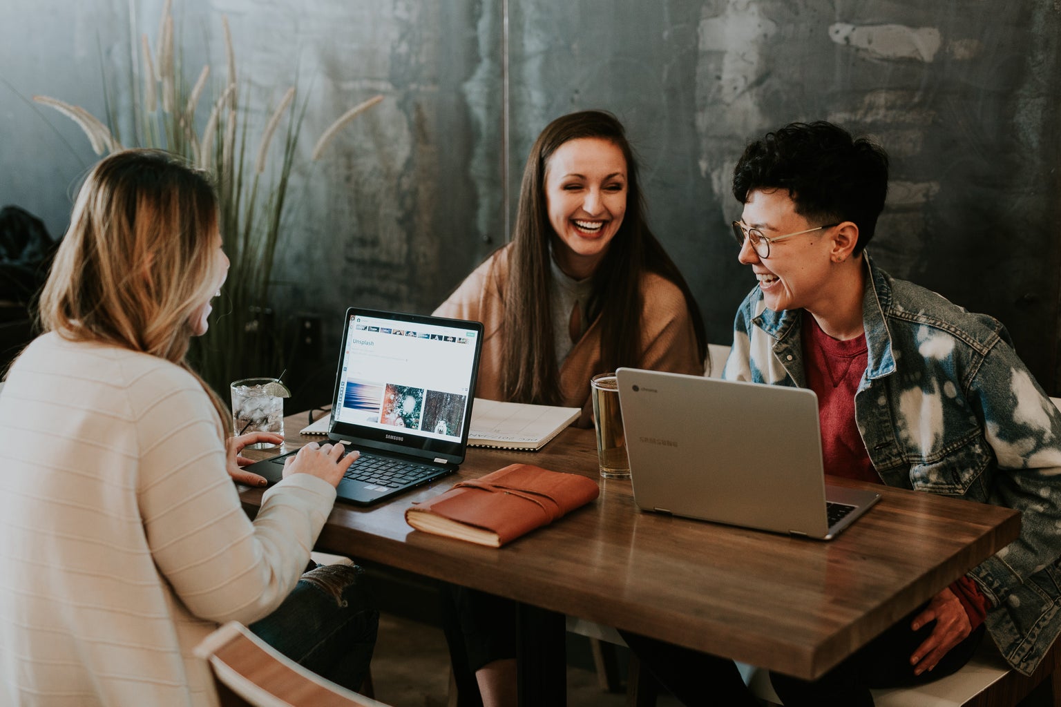 People sitting at table with laptops and laughing