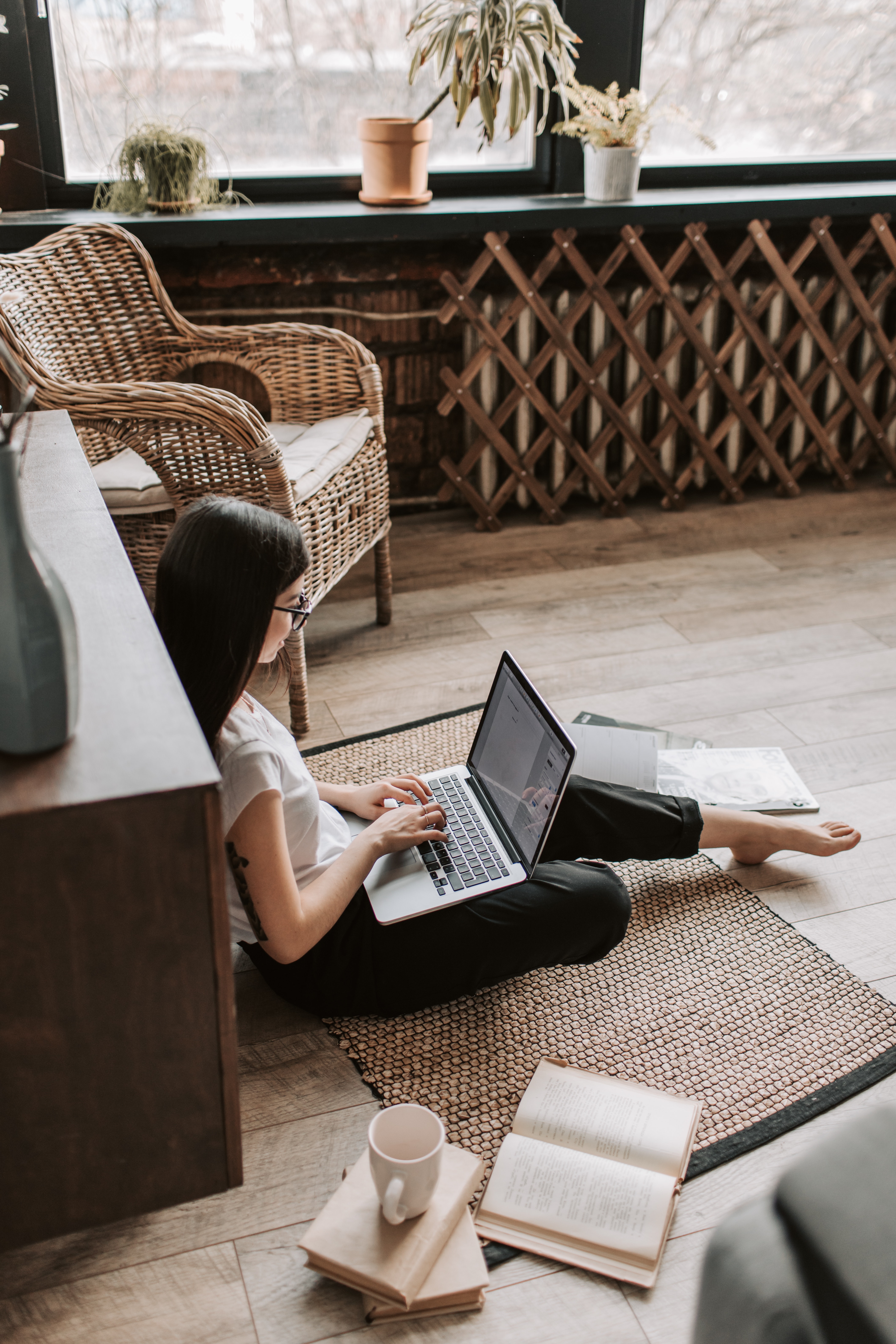A woman studies on the floor with a cup of coffee.