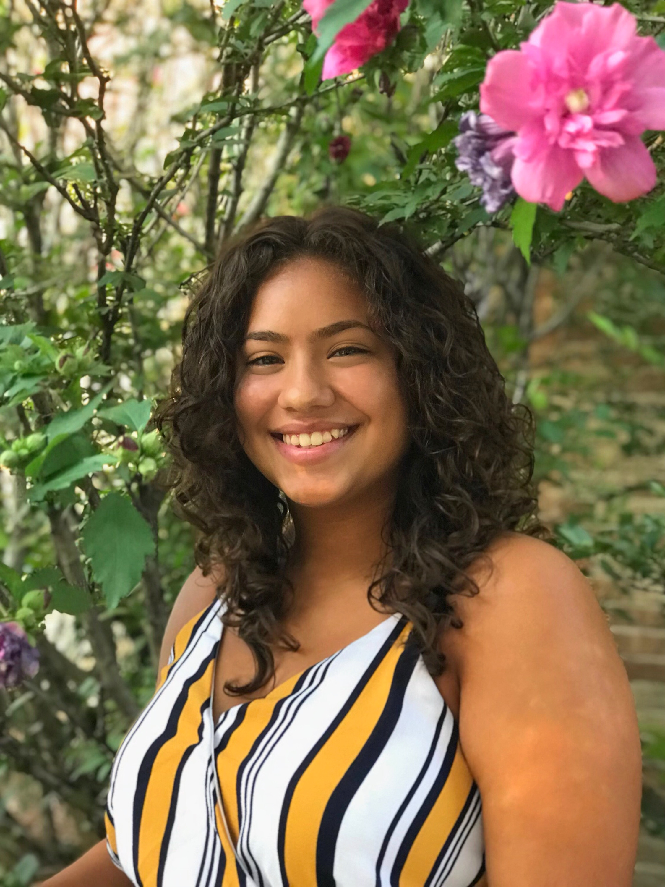J’Lynn Vellon headshot with a greenery background